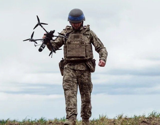Український військовий із безпілотником на тлі роботи Сил безпілотних систем ЗСУ
