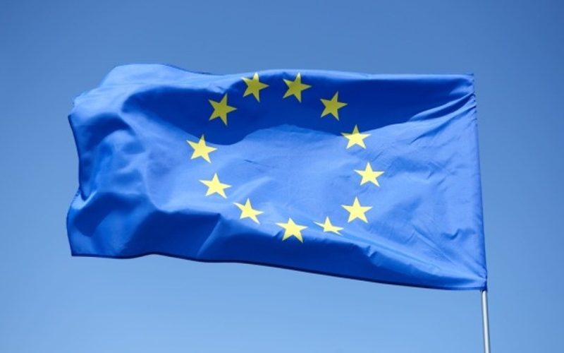 Прапор ЄС поряд із символічним зображенням санкційного пакета